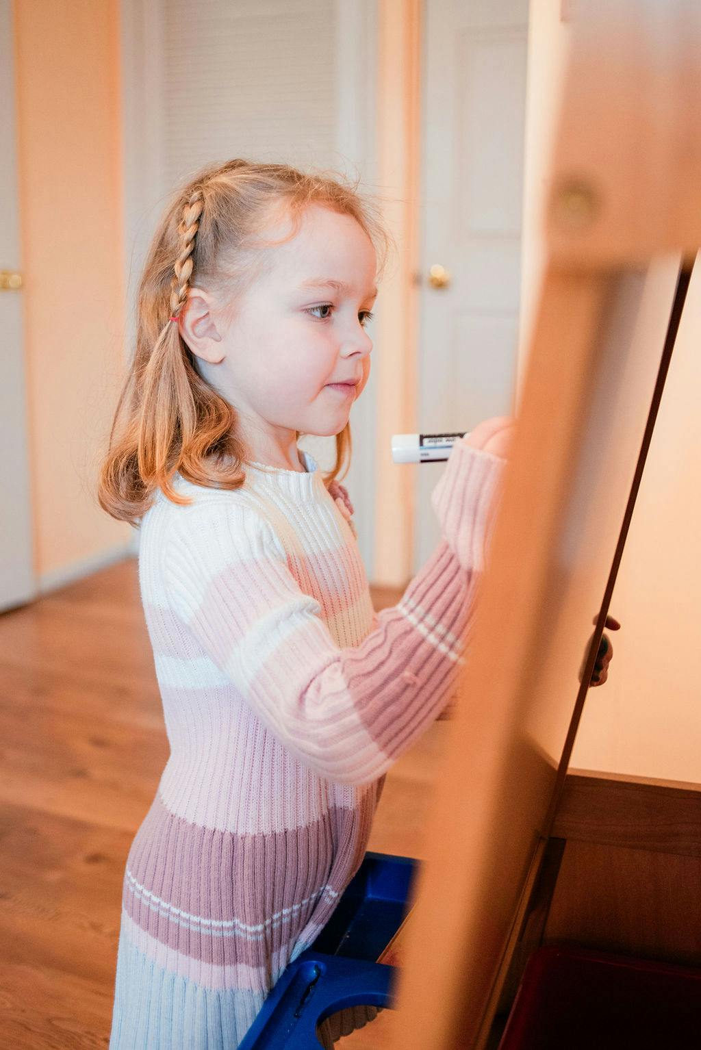 Child drawing on an easel with a marker