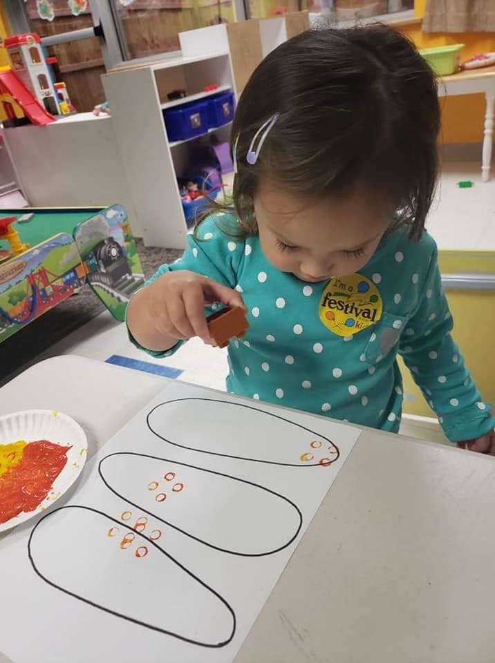 Child making art with a stamp and paint