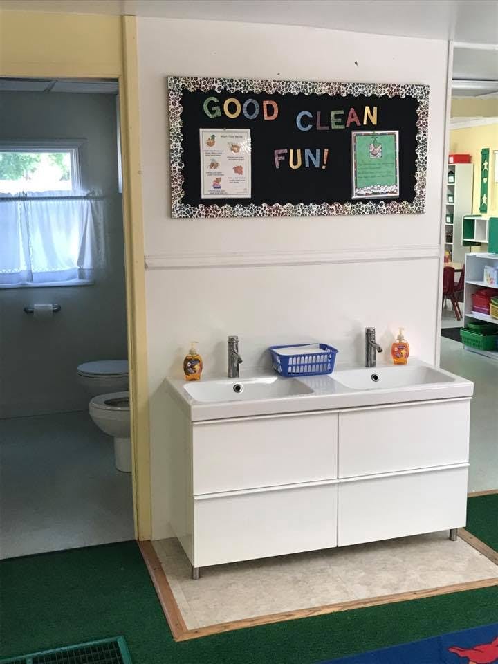 Double sink vanity with a bulletin board above reading "GOOD CLEAN FUN!"