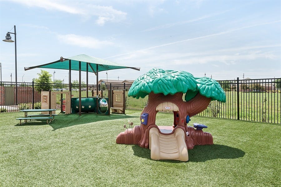 Outdoor playground with a tree-shaped play structure and a shaded area