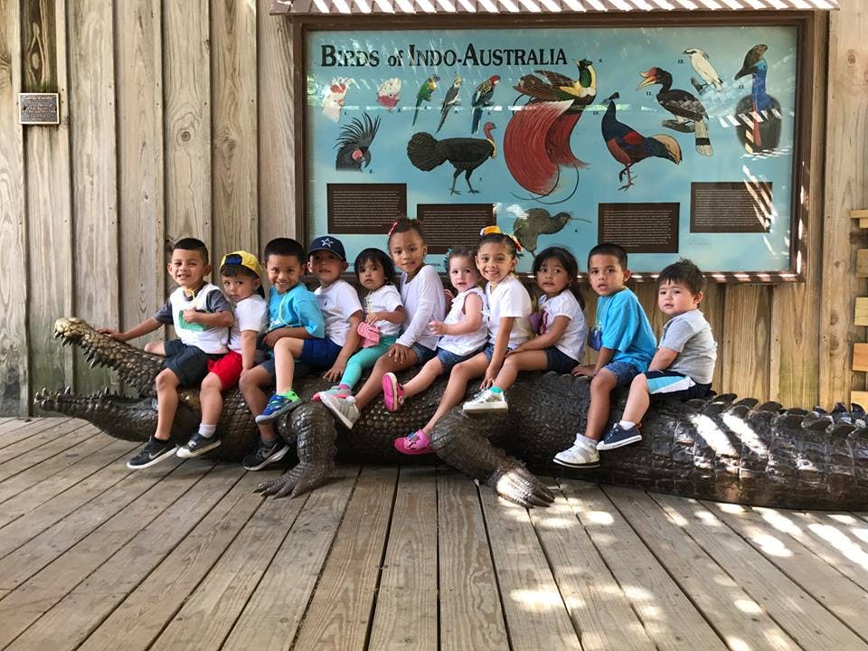 Group of children sitting on a large alligator statue