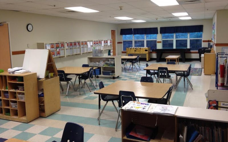 An empty classroom with small tables and chairs arranged throughout
