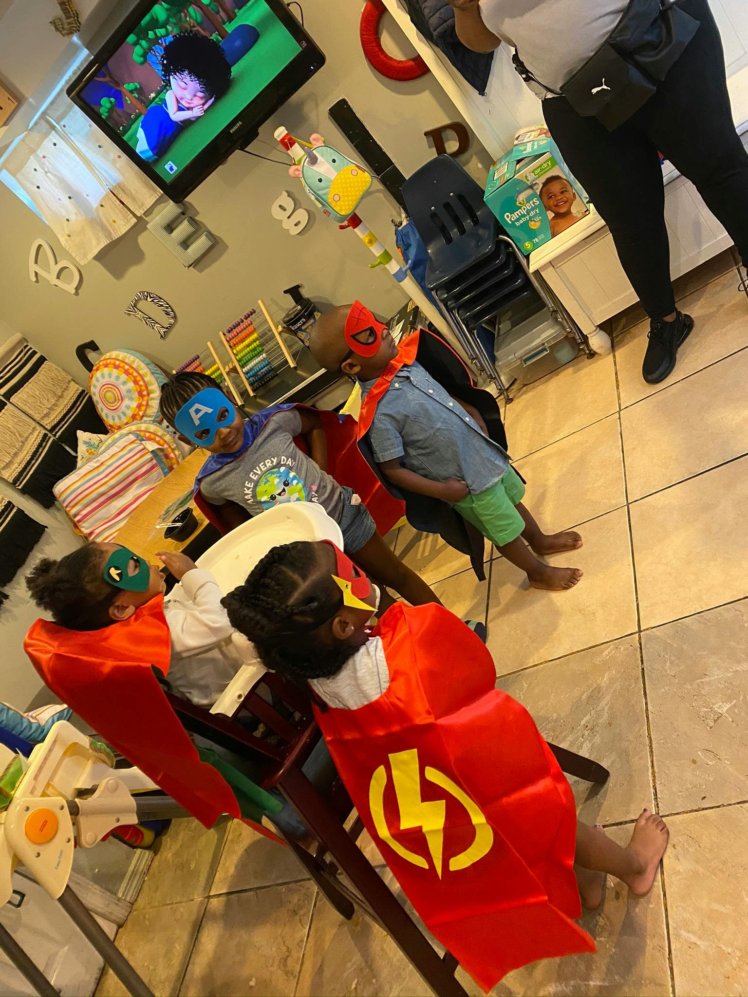 Four children wearing superhero masks and capes