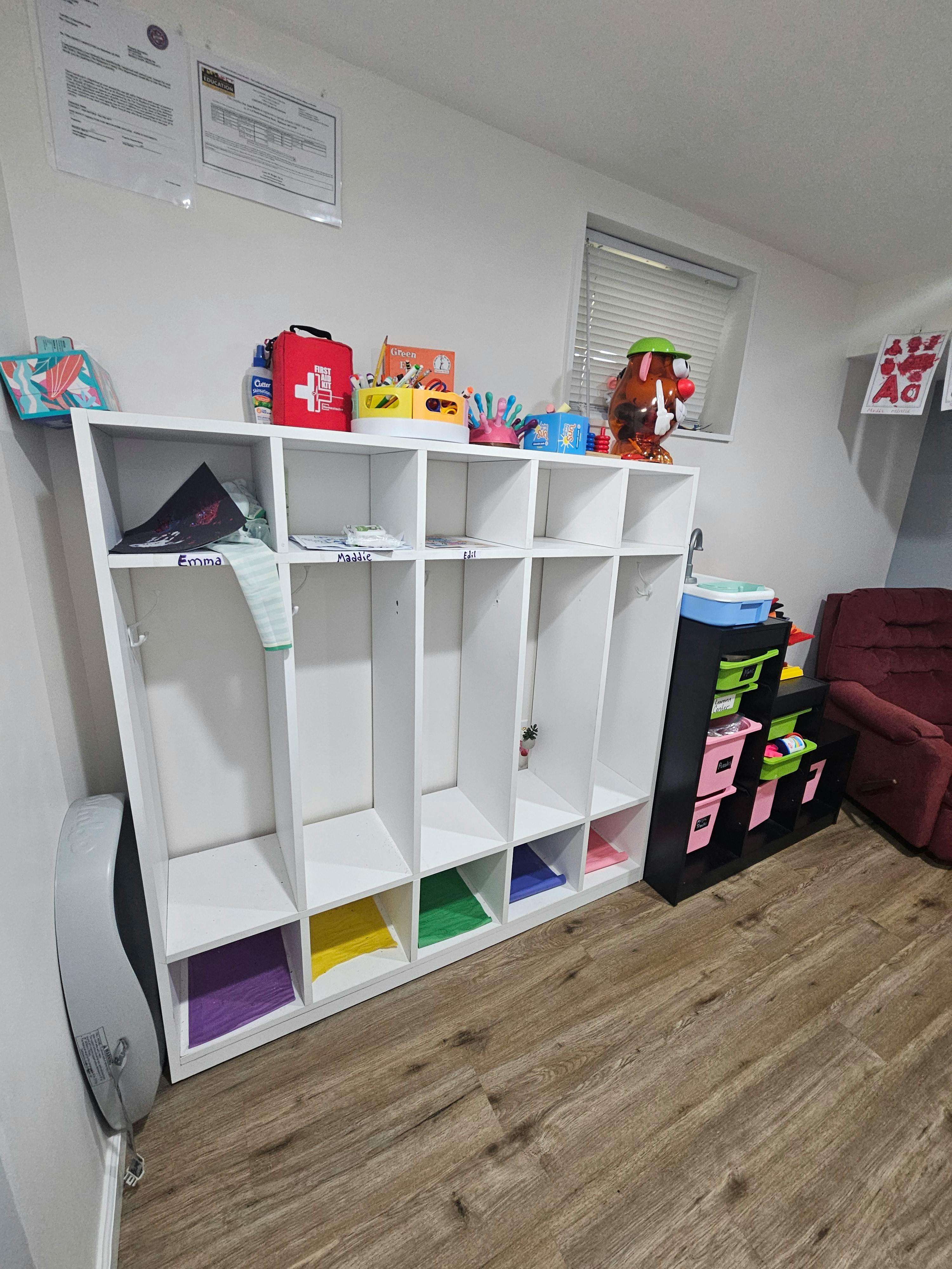 White storage cubby unit with colorful labeled compartments in a classroom