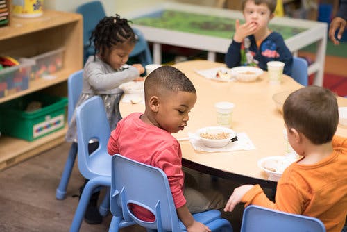Children eating at a table in a classroom