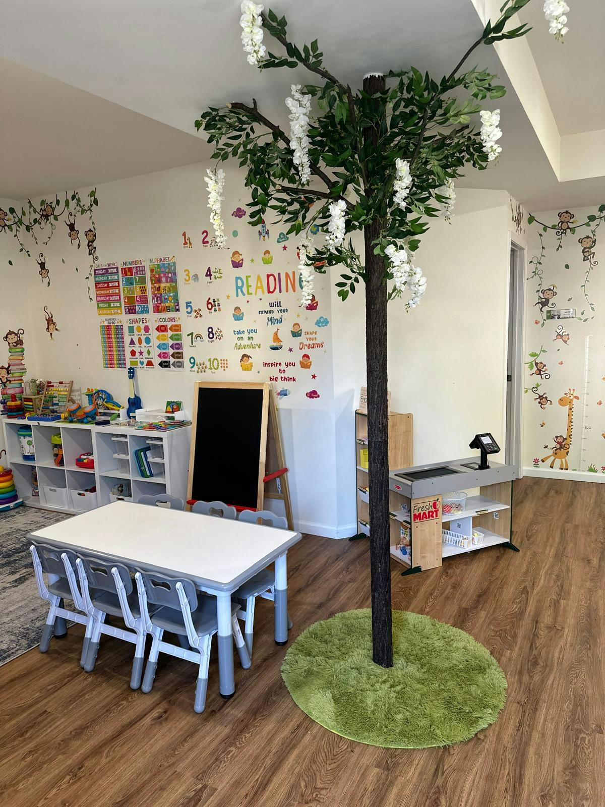 Classroom with a table and chairs, a tree prop, and learning posters on the wall
