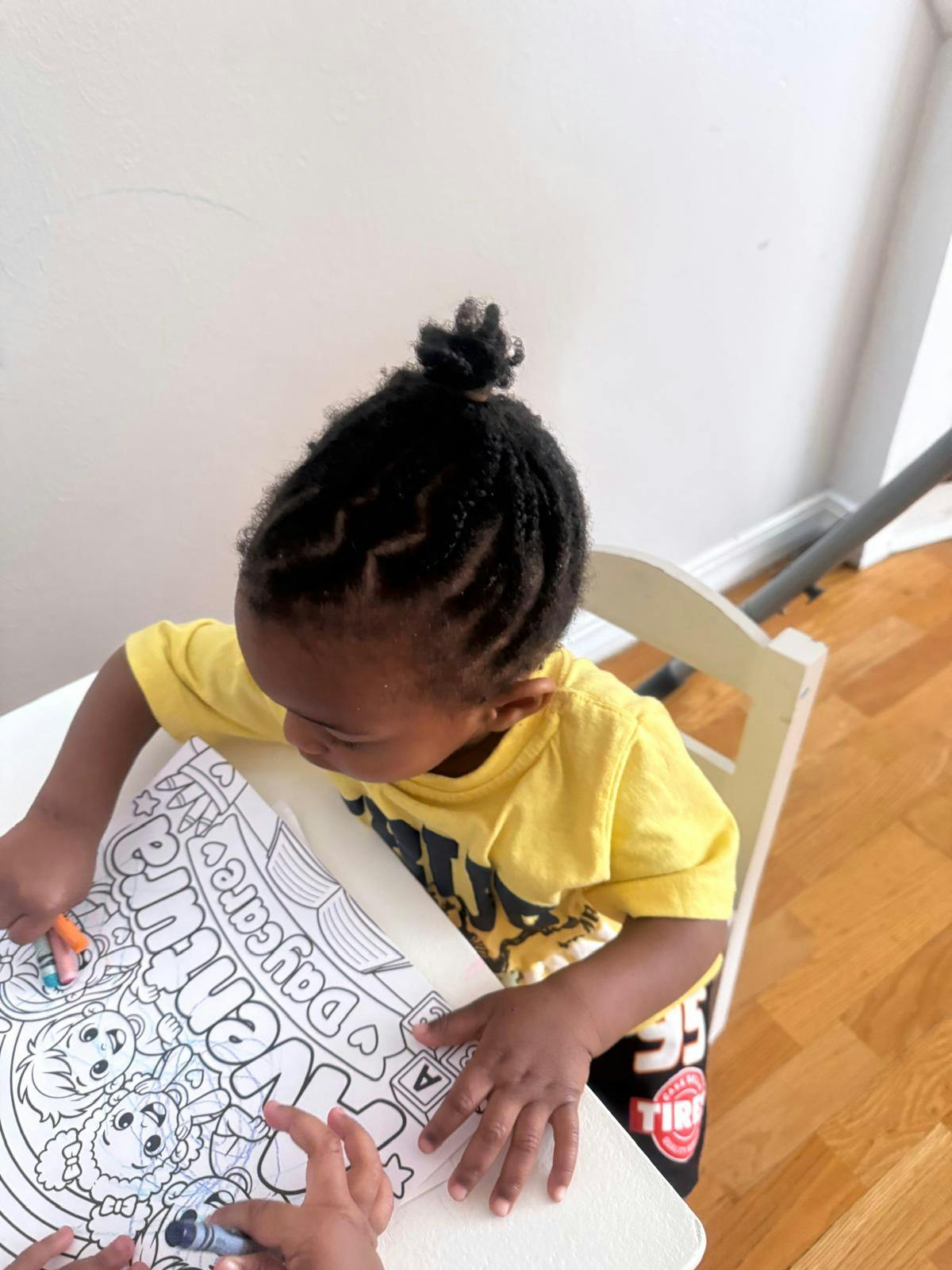 Child coloring on a paper with daycare themed illustrations