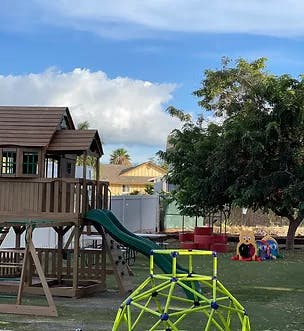 Playground with a slide, climbing dome, and playhouse