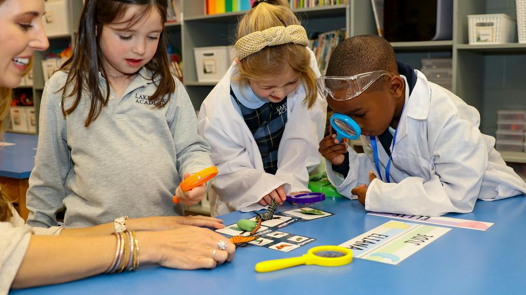 Children and an adult examining butterfly specimens with magnifying glasses