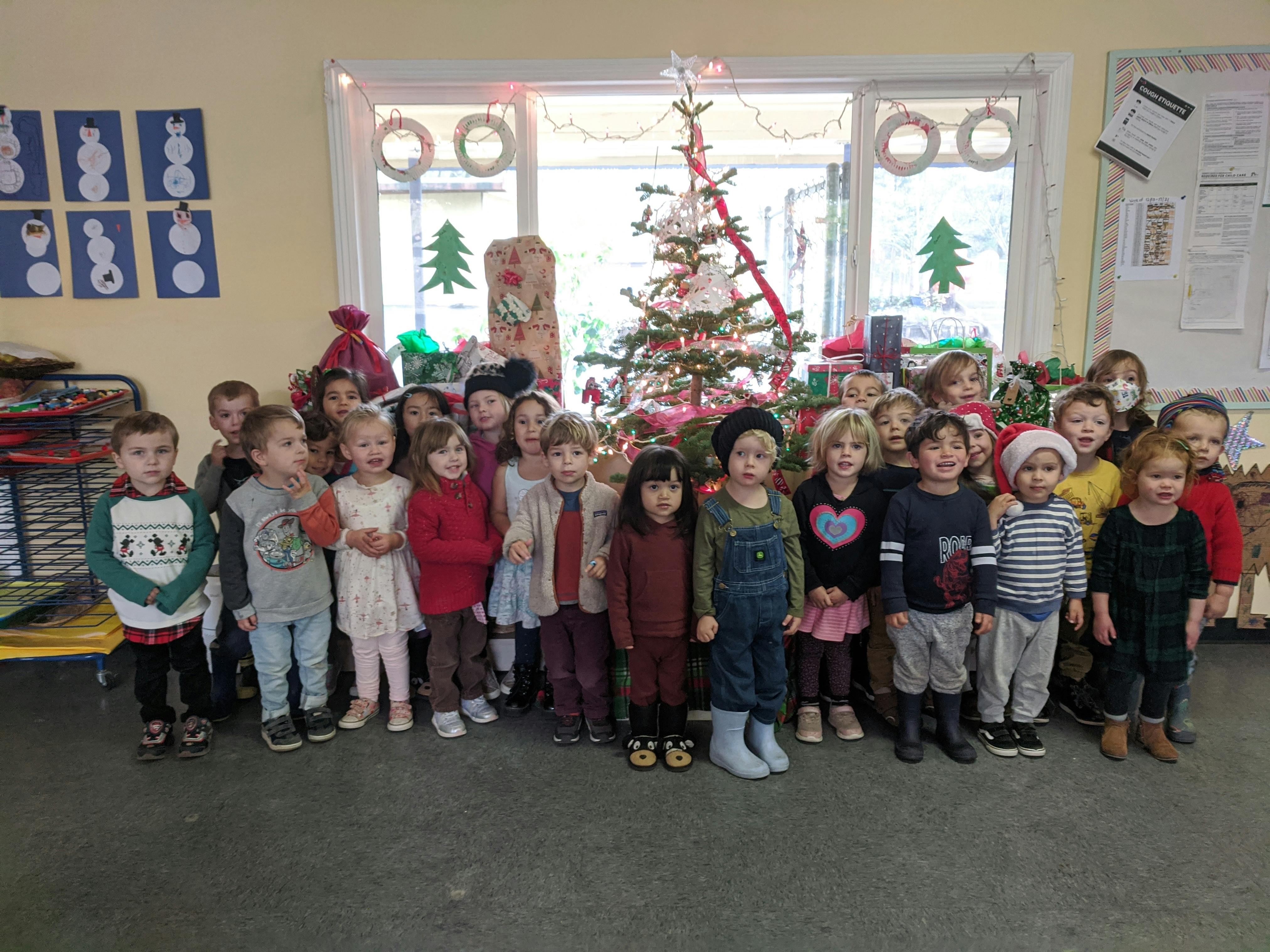 Group of children standing in front of a decorated Christmas tree