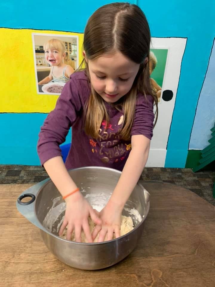 Child kneading dough in a metal bowl