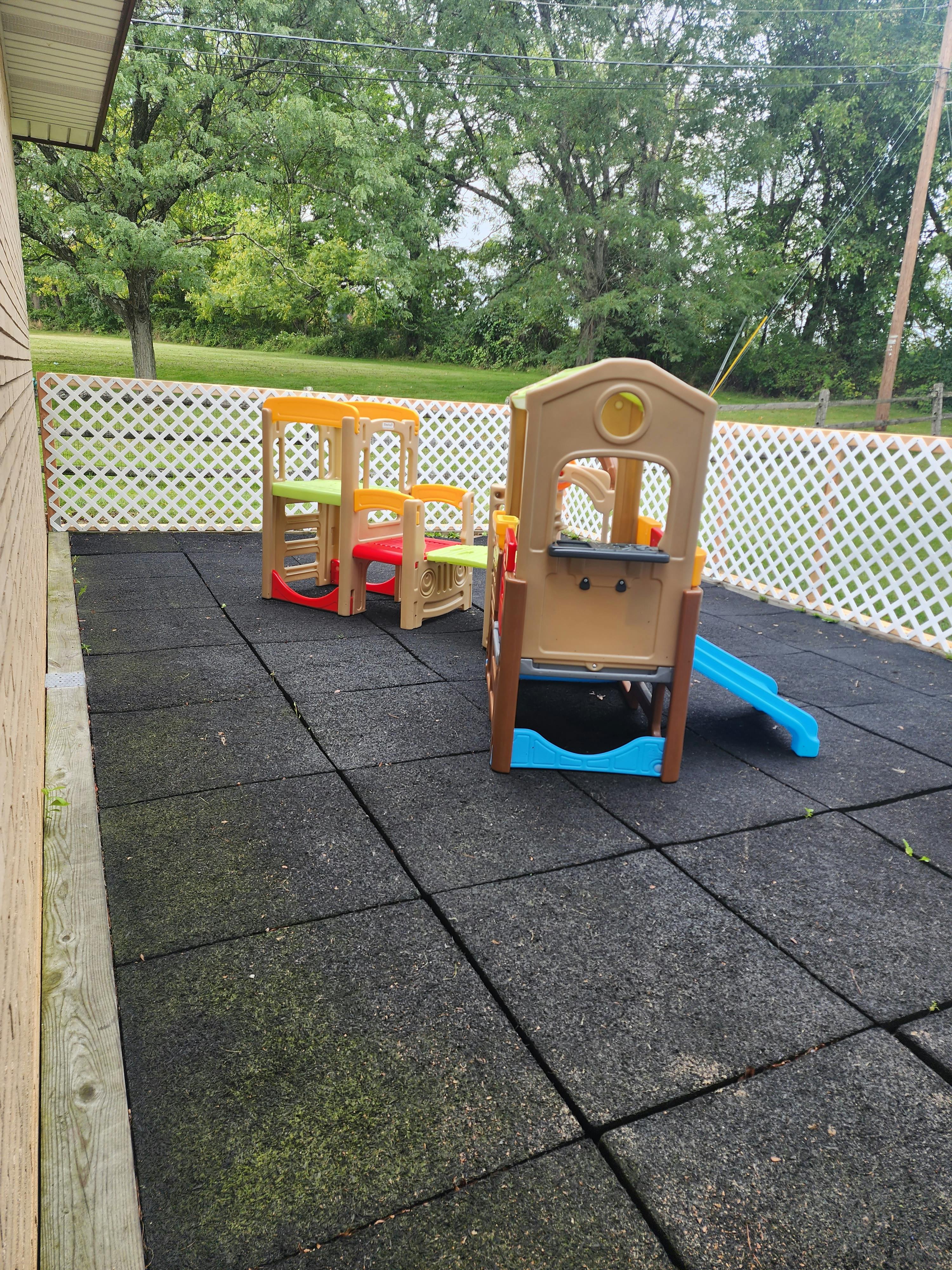 Two small outdoor play structures with slides on rubber matting
