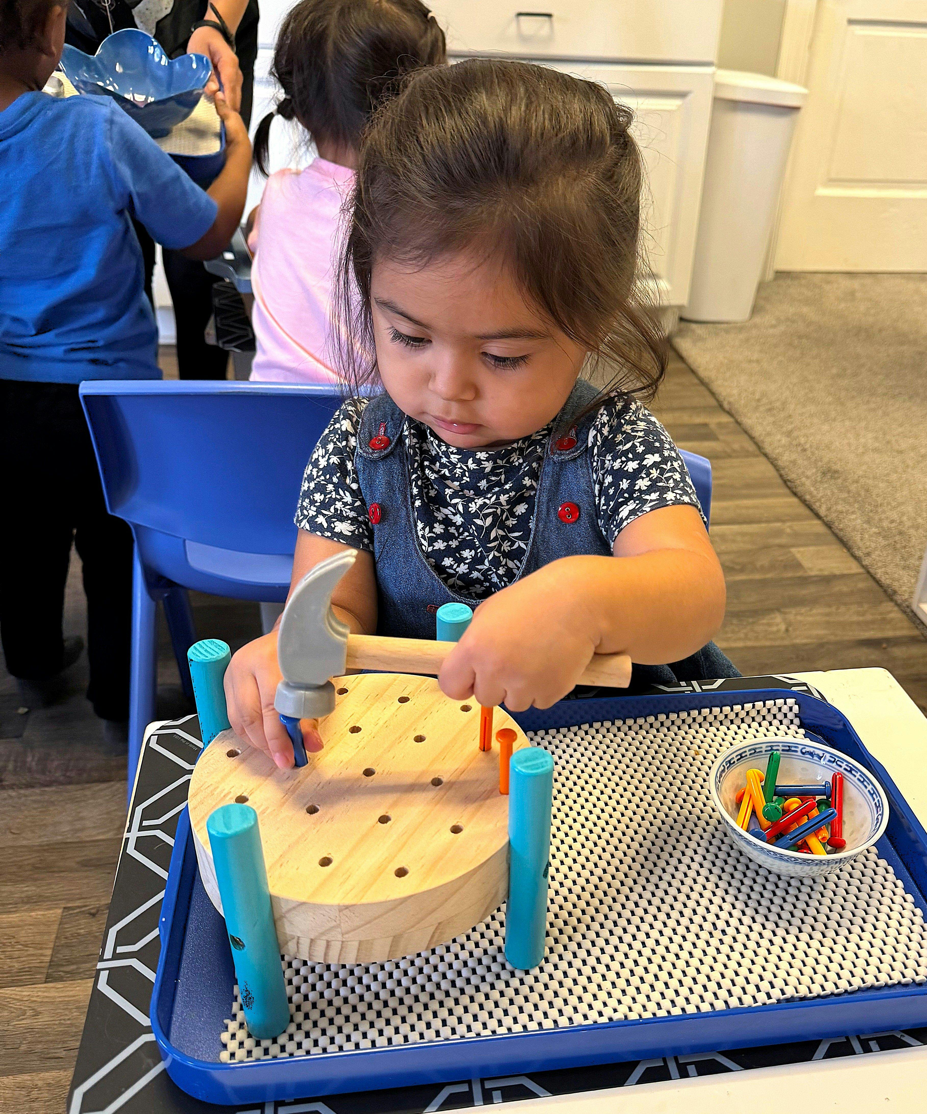 Child playing with a toy hammer and pegs
