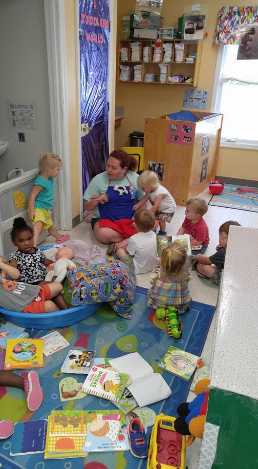 A person sitting on the floor with several children in a classroom