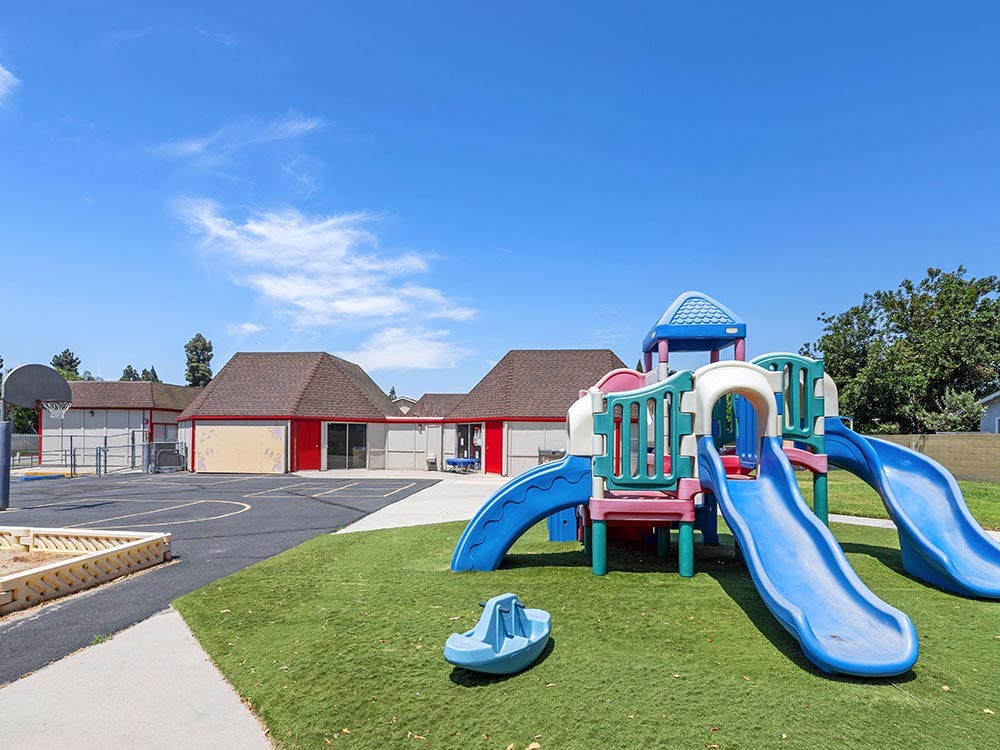 Playground with slides and a basketball court next to a building