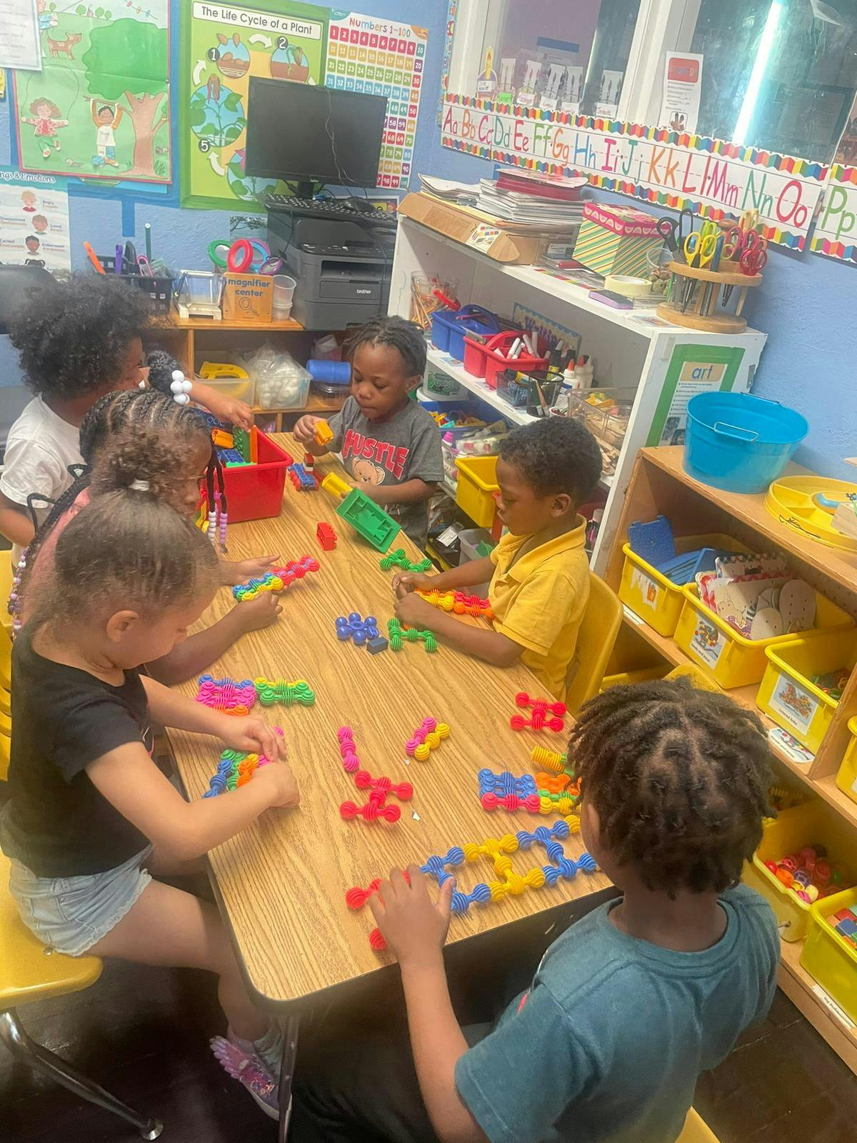Children playing with colorful building blocks at a table in a classroom