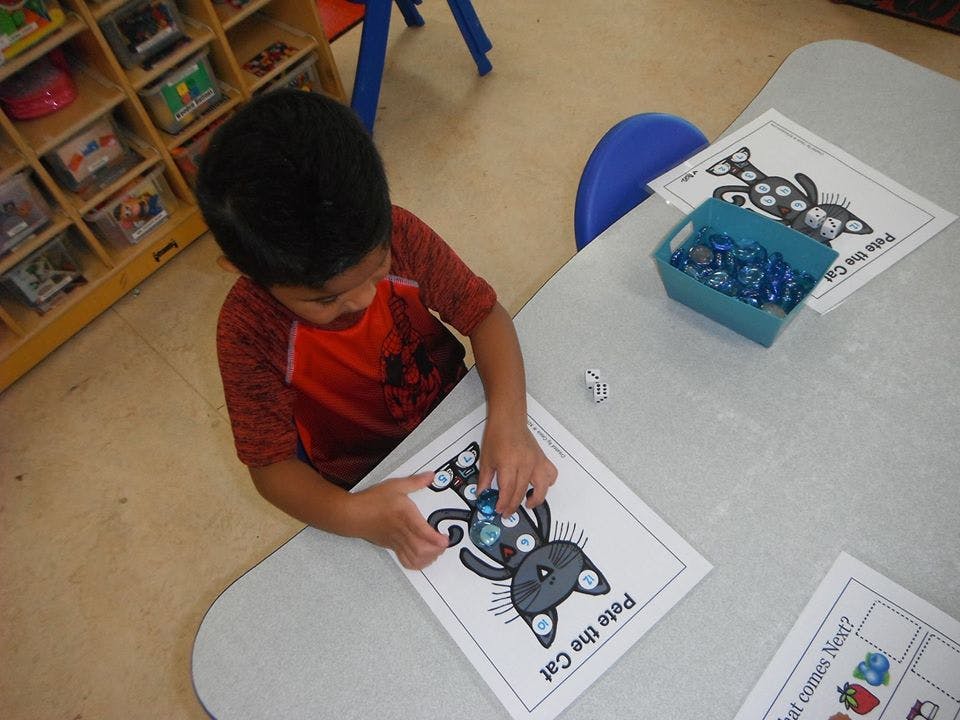 Child playing with a Pete the Cat activity sheet at a table