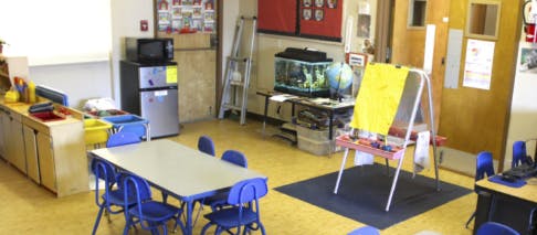 Classroom with small table and chairs, easel, and fish tank