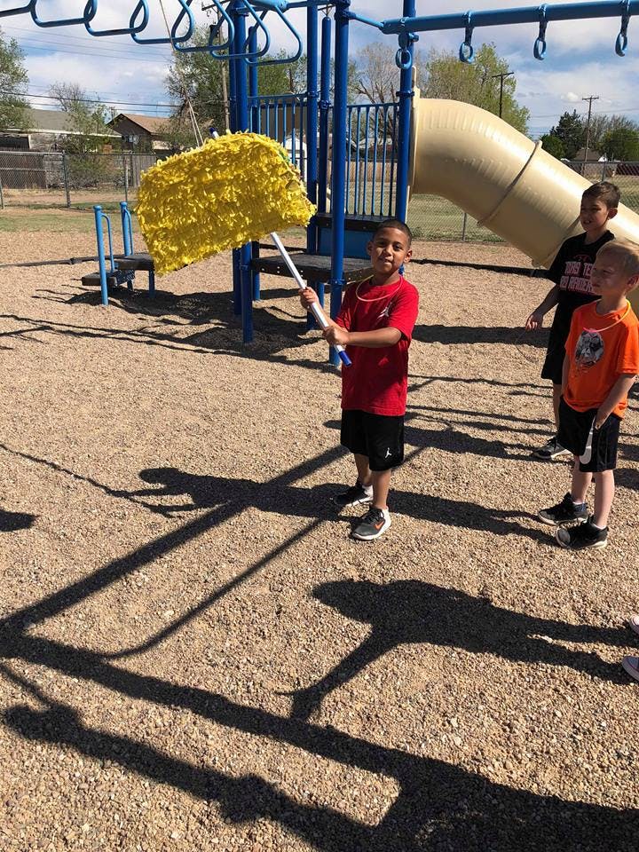 Child holding a stick to hit a yellow piñata on a playground