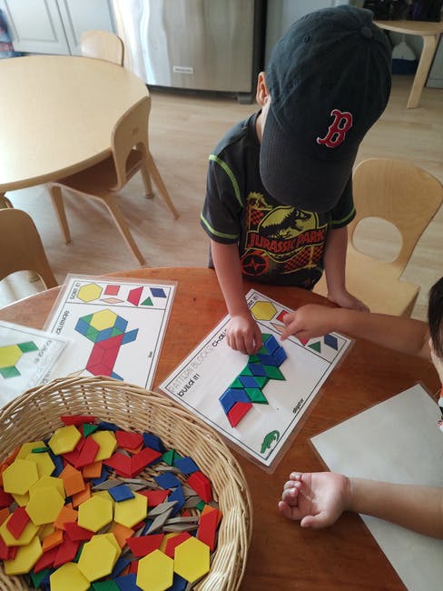 Child playing with colorful geometric shapes on a pattern card