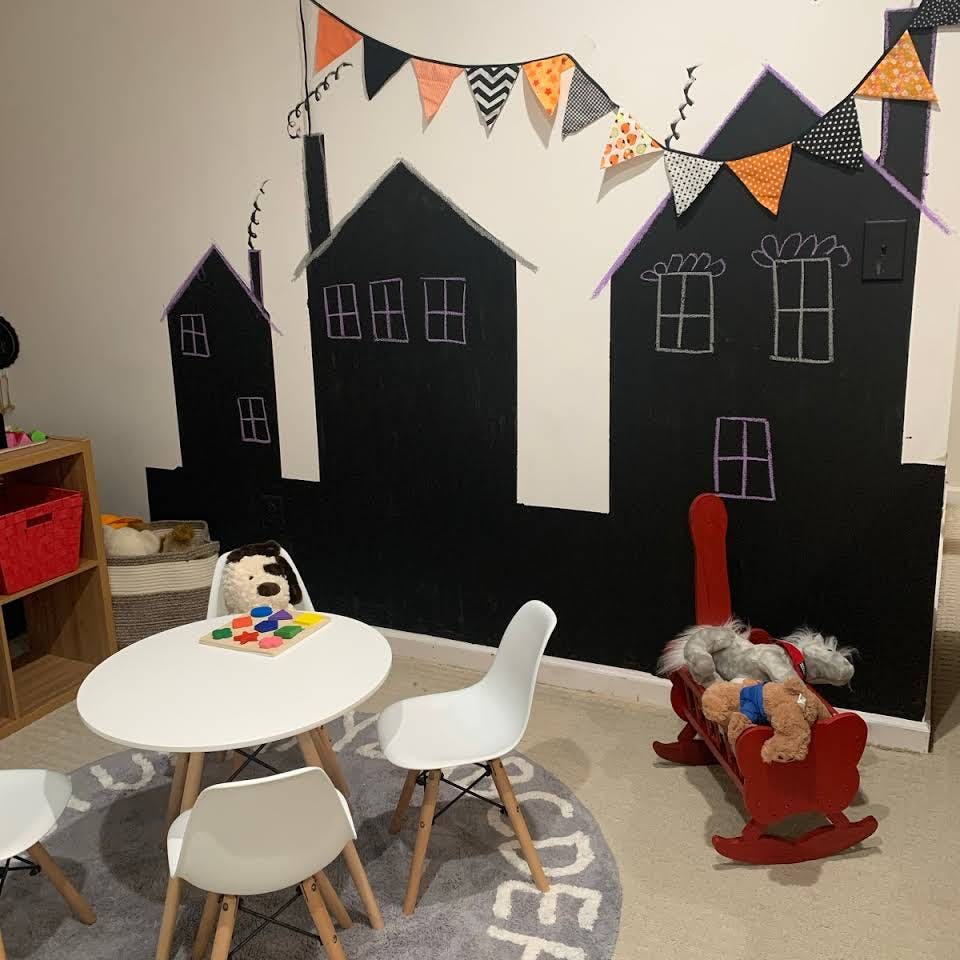 Playroom with a small table and chairs, a rocking horse, and house-shaped wall decor