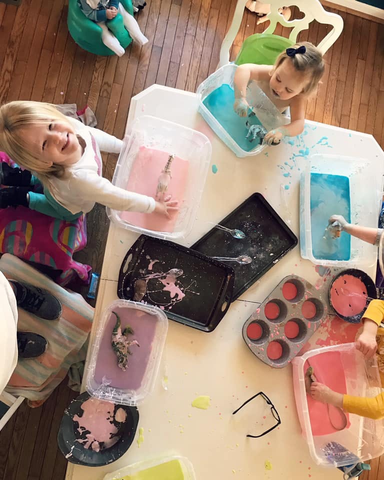 Children playing with colorful liquids in containers on a table