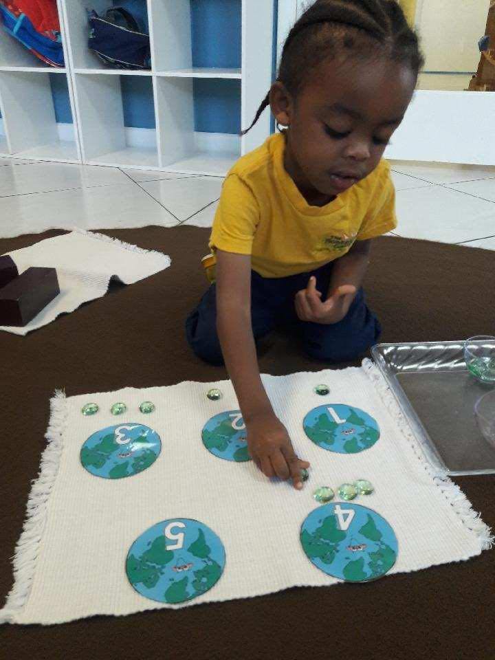 Child kneeling and placing a marble on a numbered mat