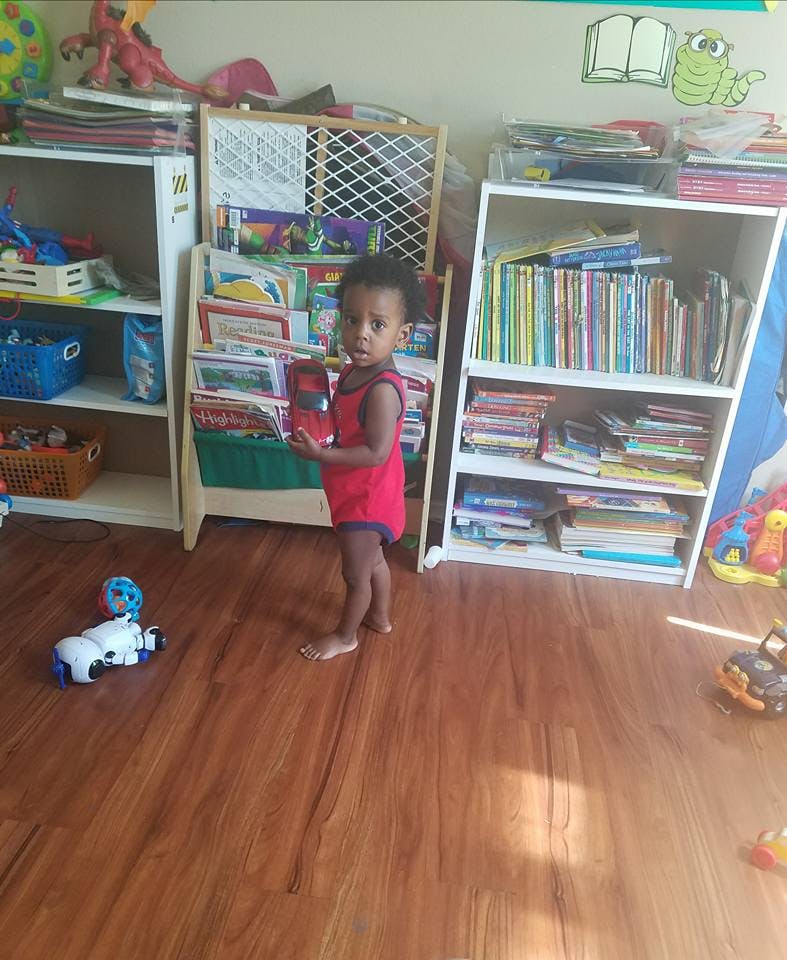 Child standing in a room with bookshelves
