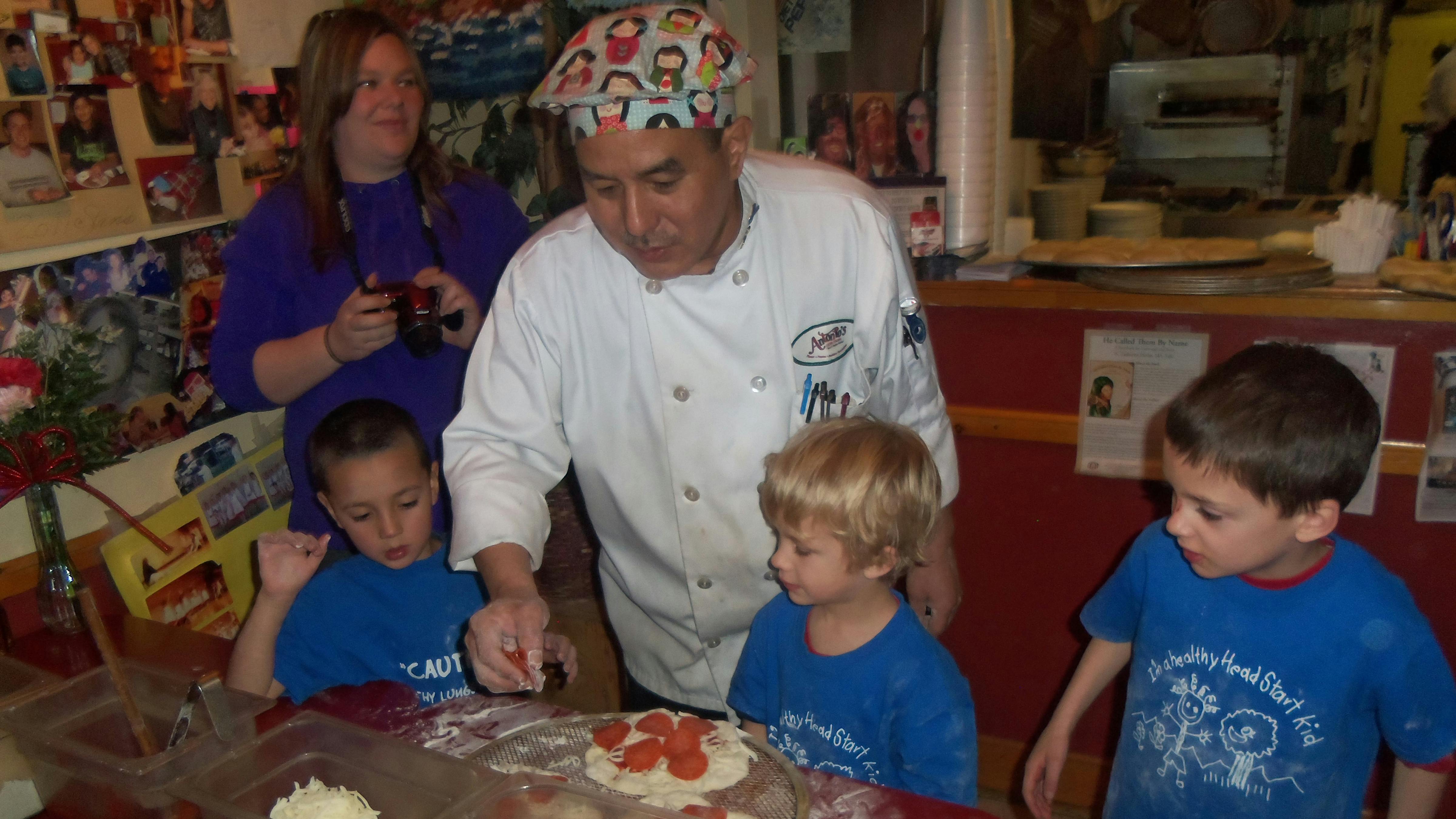 Chef helping children make pizza