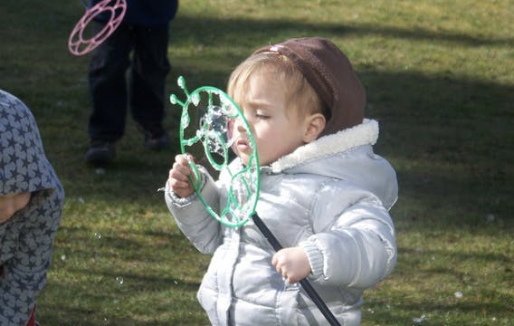 Child in a winter coat holding a bubble wand