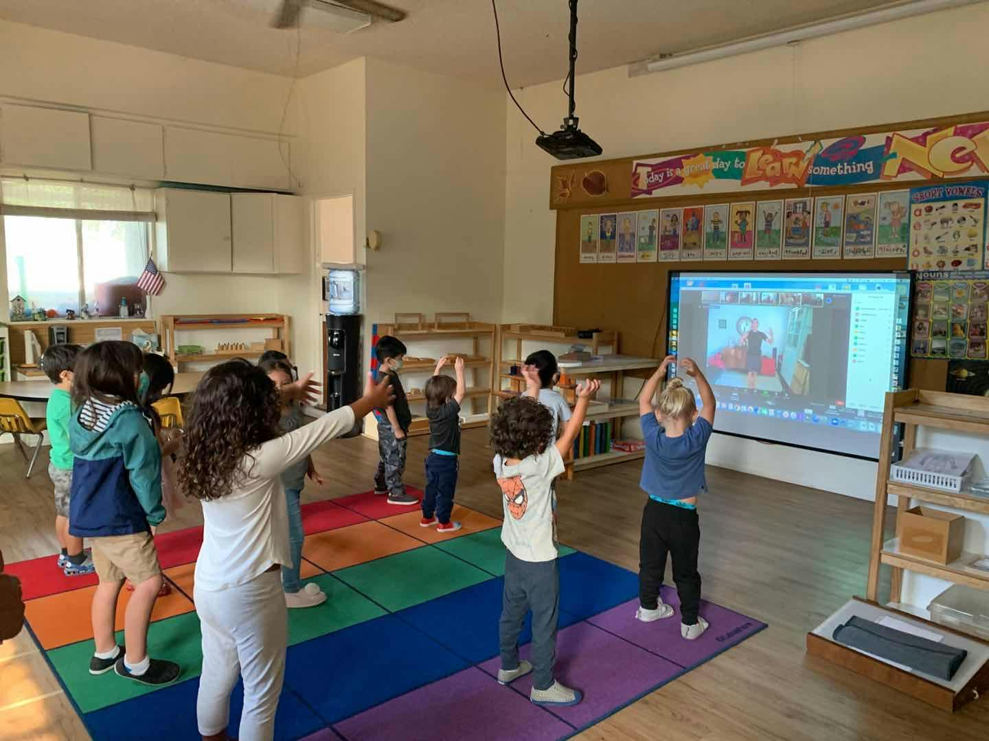 Children in a classroom doing exercises while watching a screen