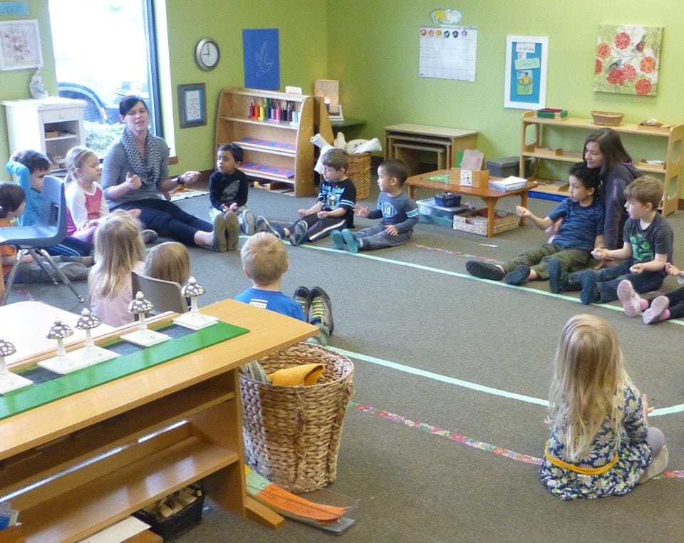 Adult and children sitting on the floor in a classroom