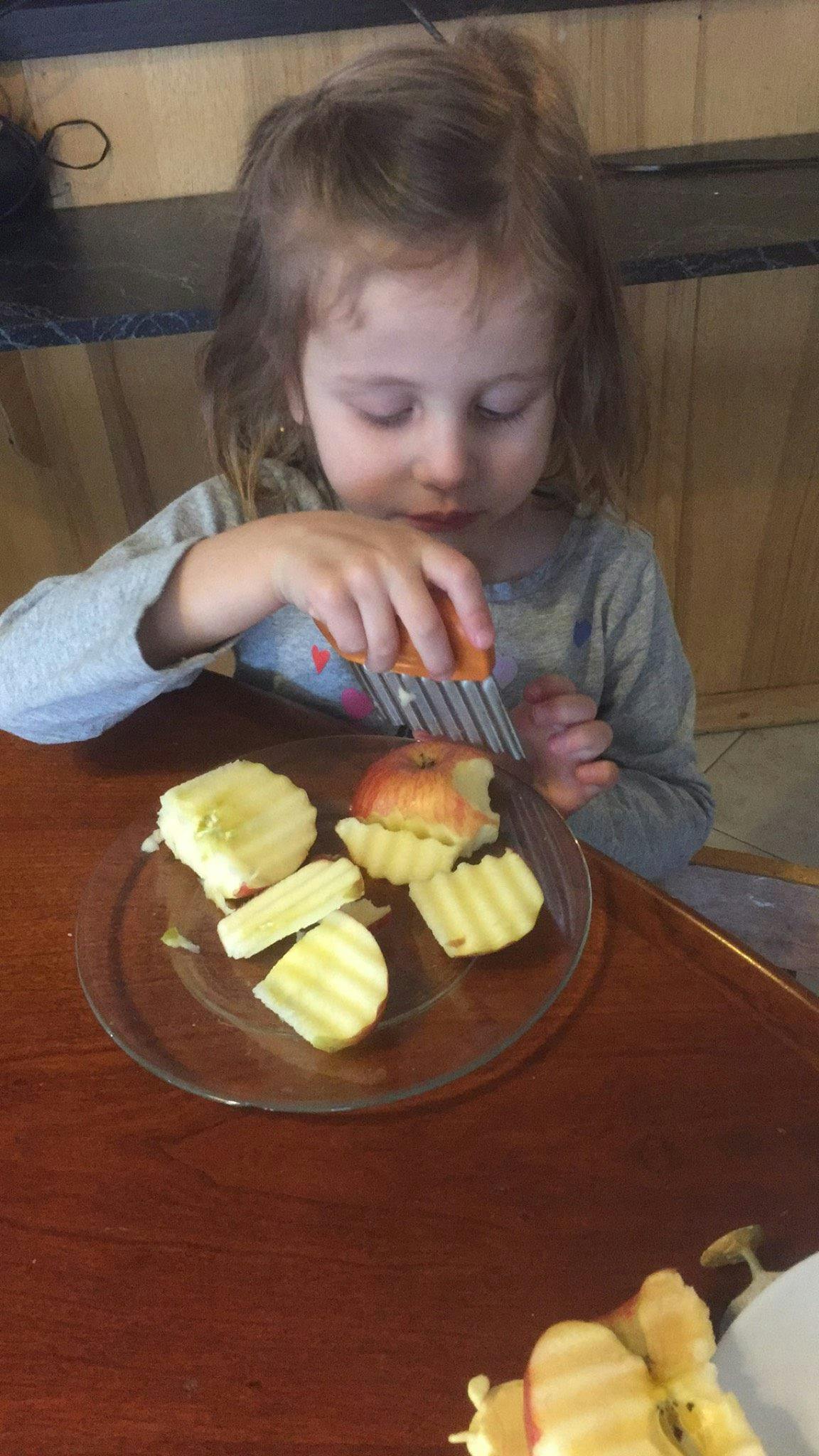Child cutting an apple with a crinkle cutter