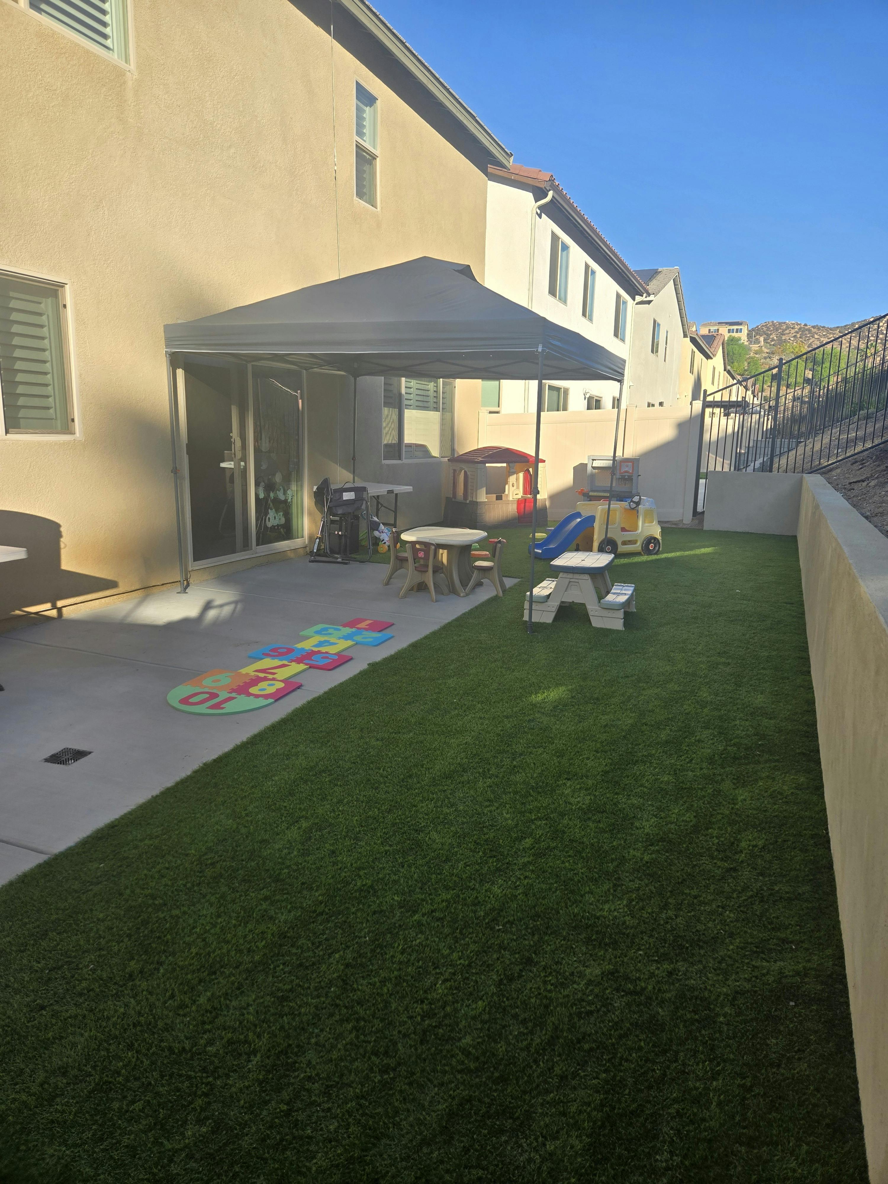 Backyard patio with a canopy, children's play area, and a grassy lawn
