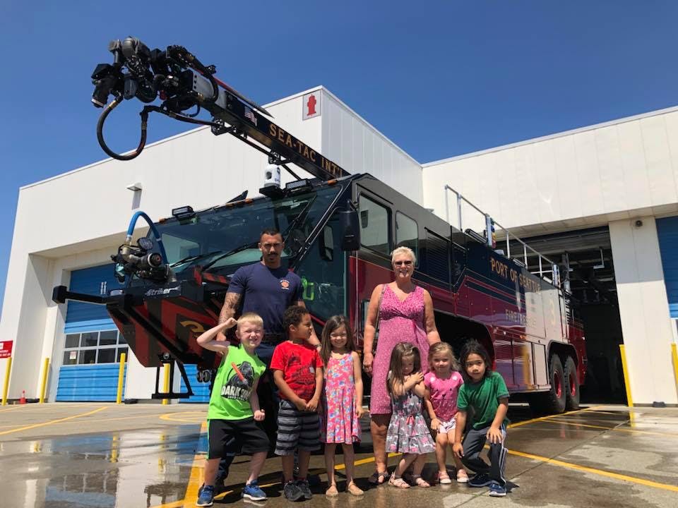 Adults and children standing in front of a fire truck