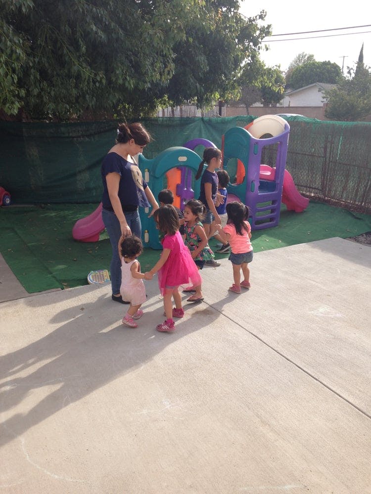 Adult and children playing outdoors near a colorful play structure