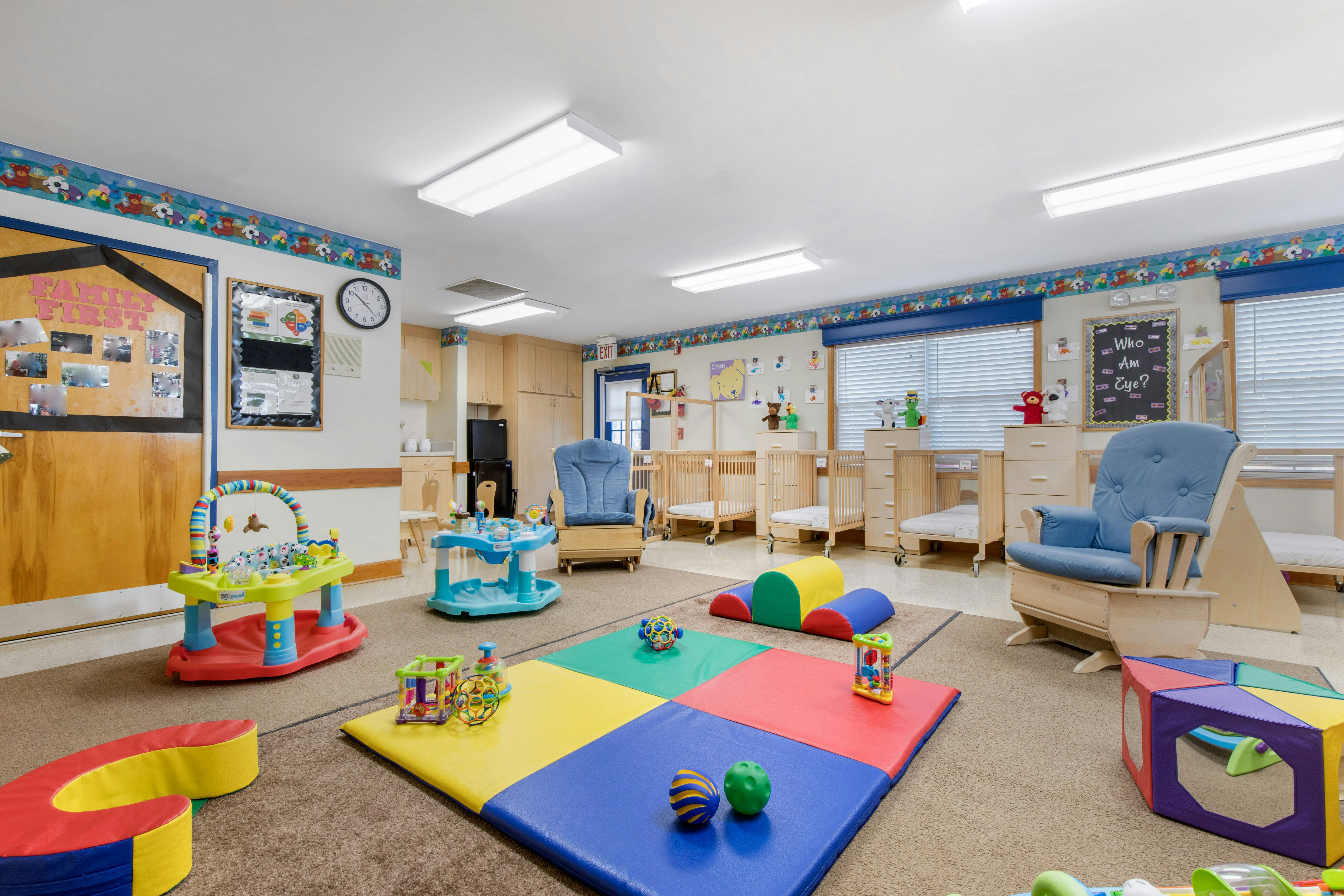 a childcare room with play mats, cradles, and activity toys