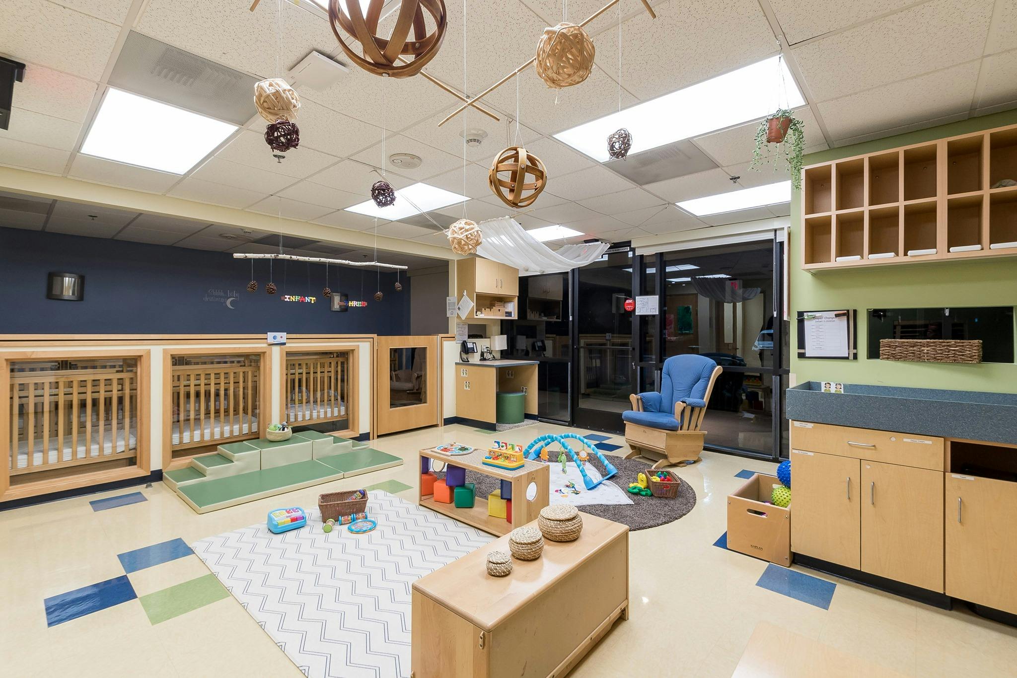 Nursery room with cribs, play mats, and changing station