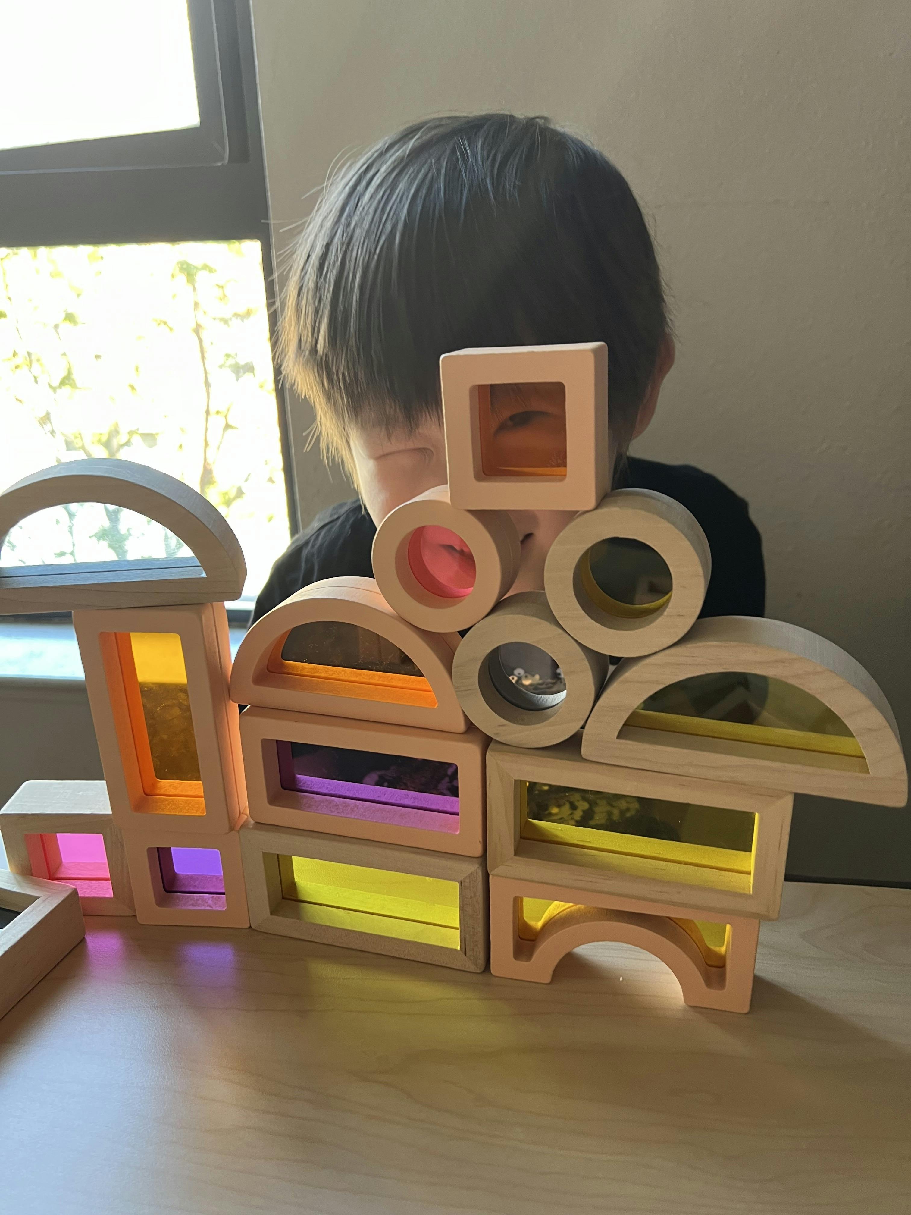 Child looking through colorful rainbow blocks on a table