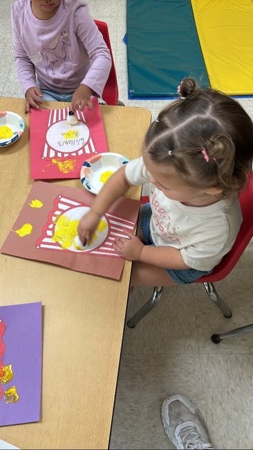 Child finger painting at a table