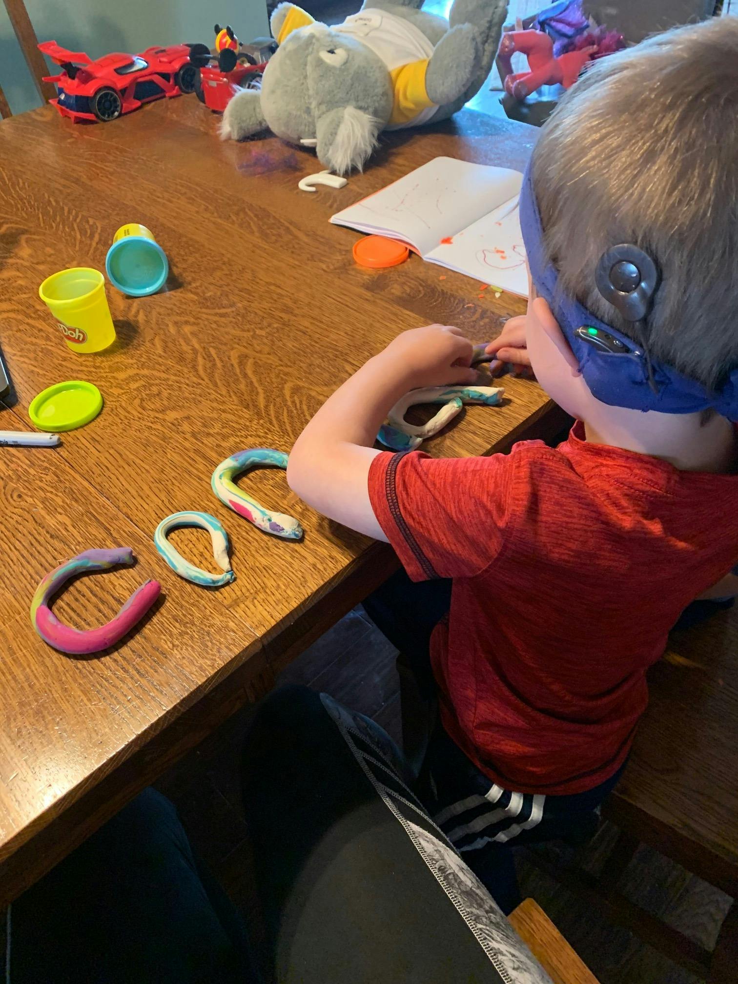 Child playing with colorful clay at a wooden table