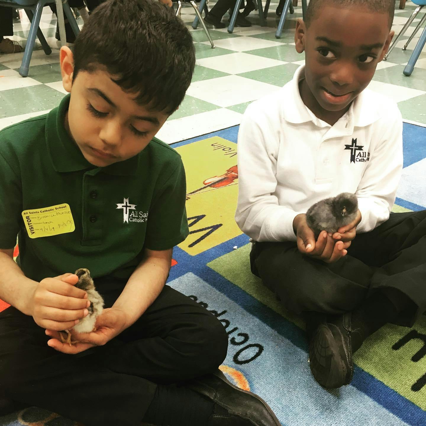 Two children holding small animals in a classroom