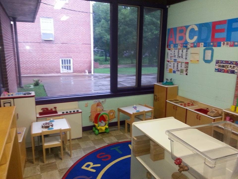 Classroom with small tables and chairs, alphabet on wall, and large window