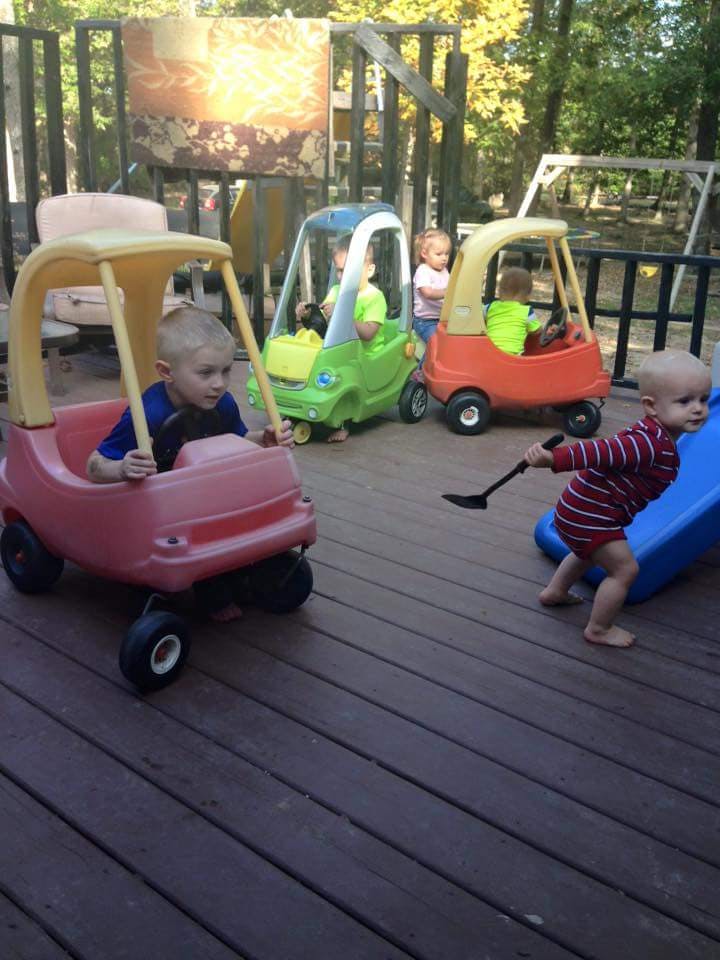 Children playing with toy cars and a slide on a wooden deck