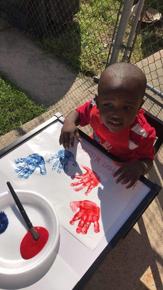 Child making handprints on paper with paint
