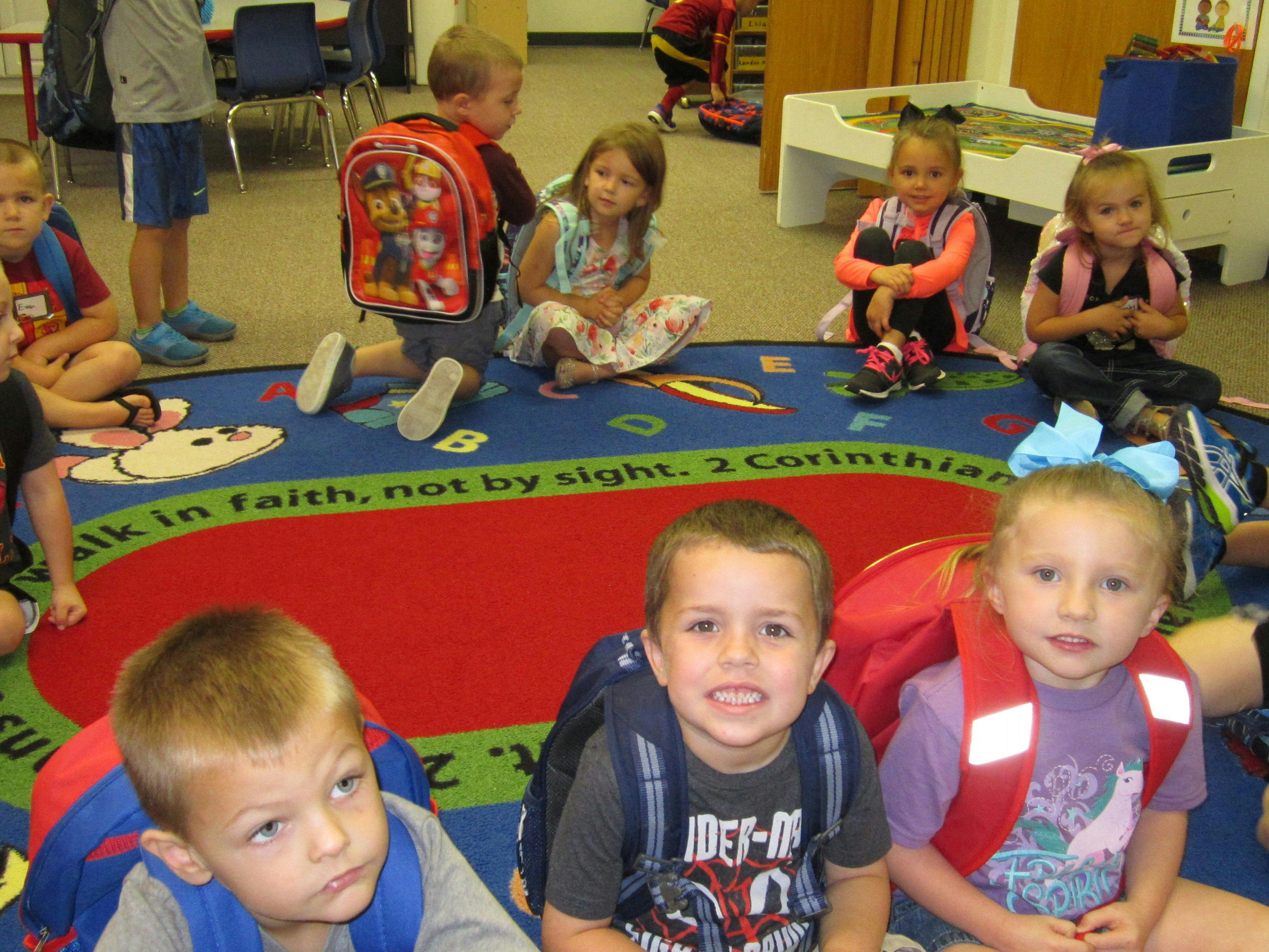 Children sitting on a colorful rug in a classroom