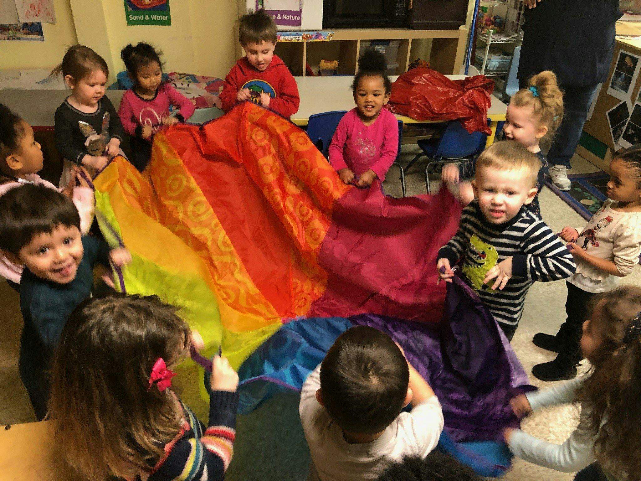 Group of children playing with a large rainbow parachute