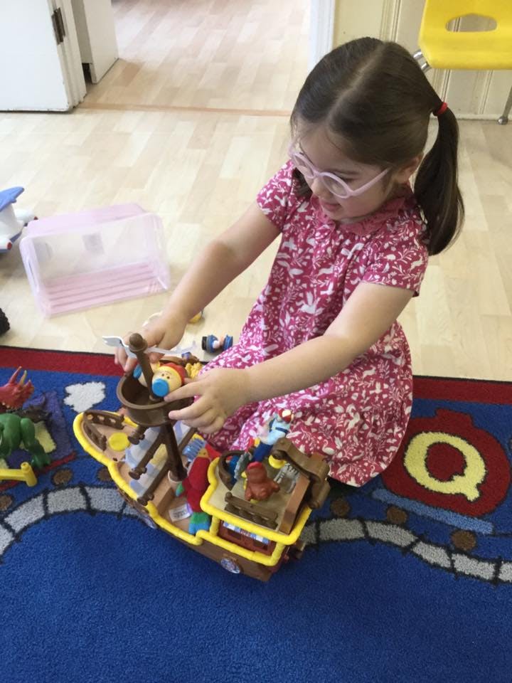 Child playing with a toy boat on a rug