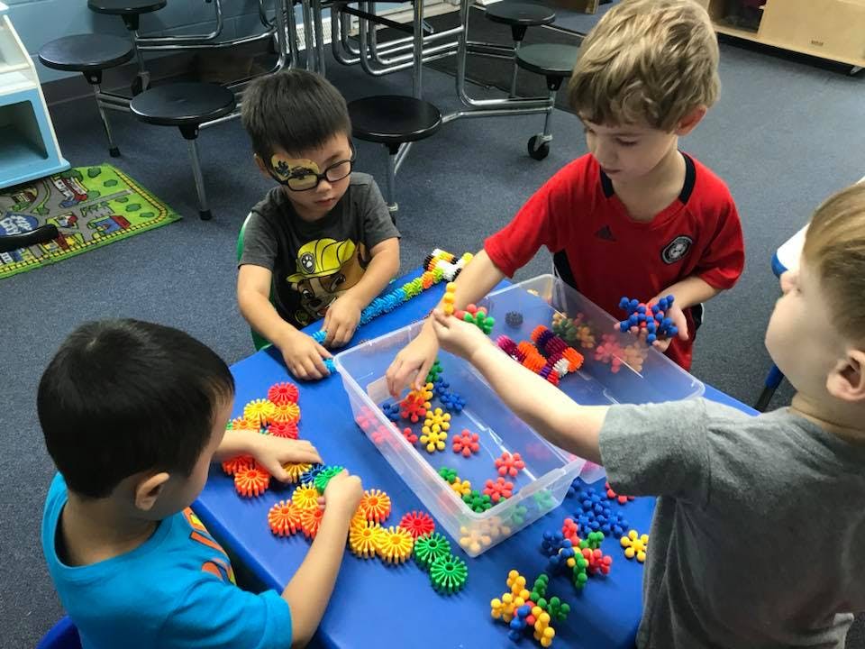 Children playing with colorful interlocking toys at a table