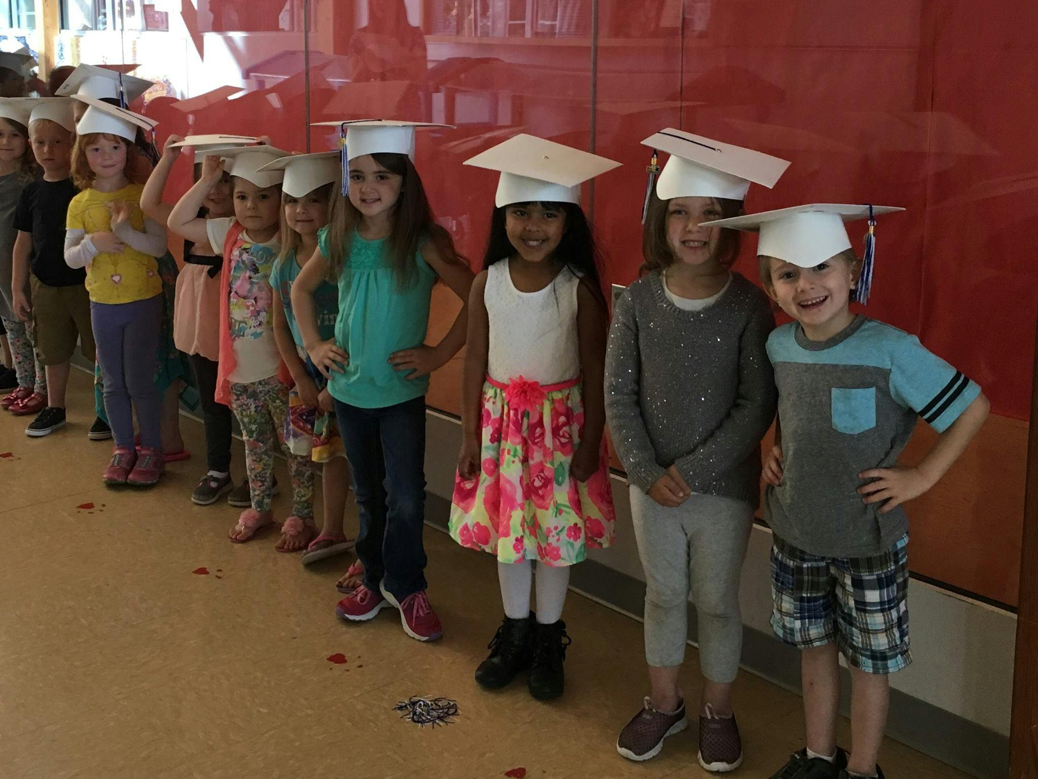 Line of children wearing graduation caps